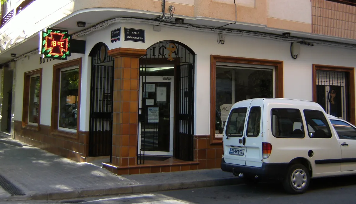 Fachada de la farmacia La Botica antes de la reforma, con diseño anticuado, rótulo no visible y escaparate cargado que limita la visibilidad desde la calle"