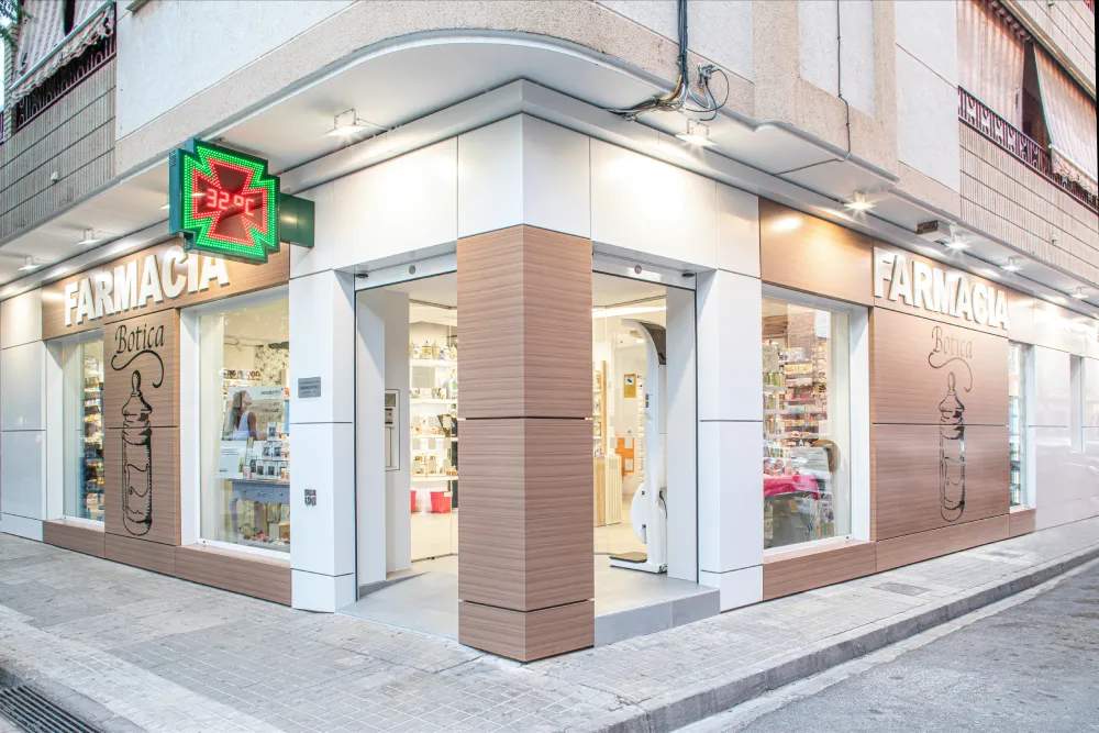 Vista exterior completa de la farmacia La Botica reformada, integrada en su entorno urbano con imagen renovada, orden visual y rotulación efectiva