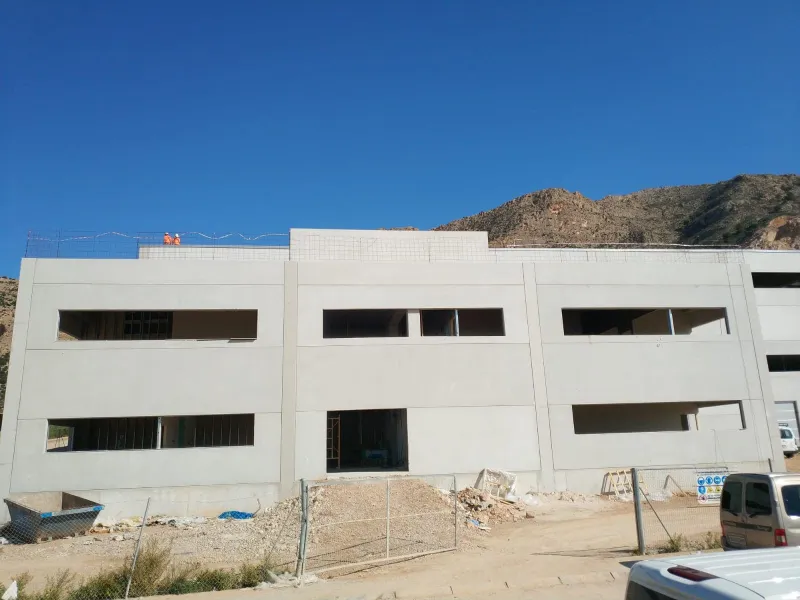 Vista lateral de la fachada de Nuovvo durante las obras, con materiales expuestos y andamiaje